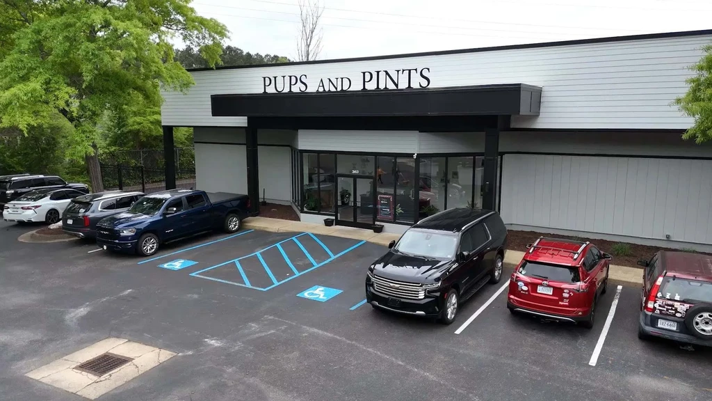 Modern white 'Pups and Pints' building exterior with parking lot.