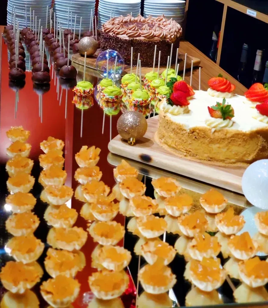Mirrored dessert buffet with tartlets, cake pops, and two large cakes.