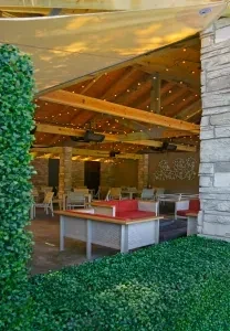 Outdoor lounge patio with string lights, stone walls, and red seating.