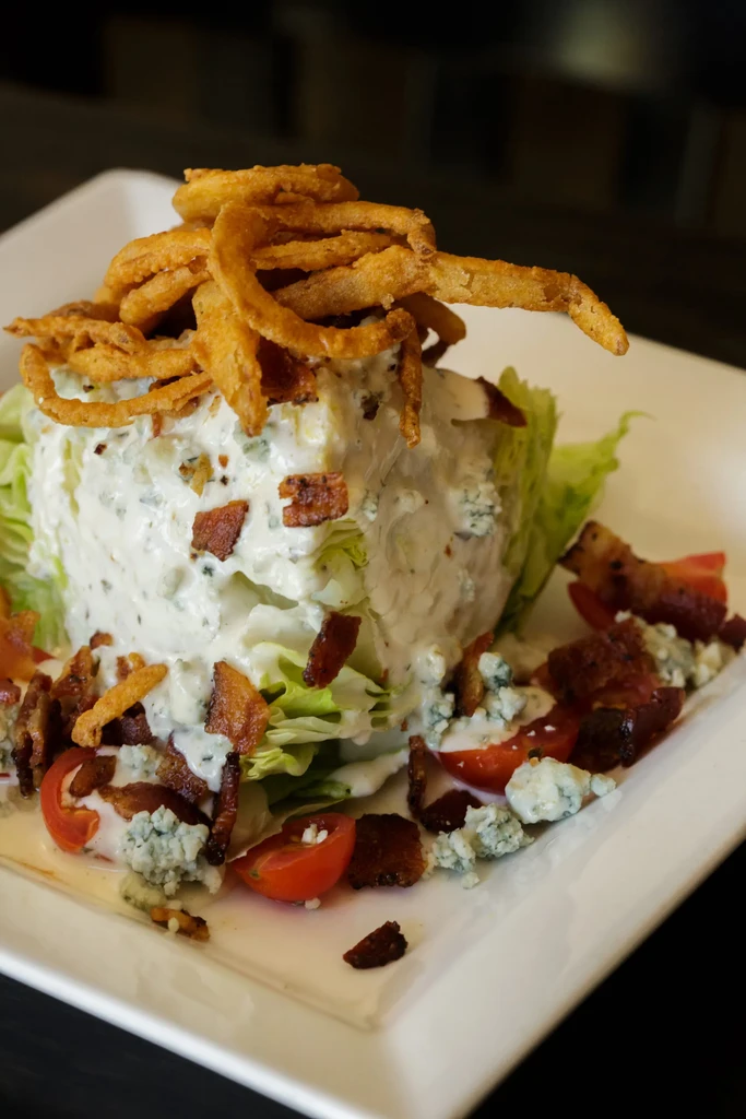 Iceberg wedge salad with blue cheese, bacon, tomatoes, fried onions.