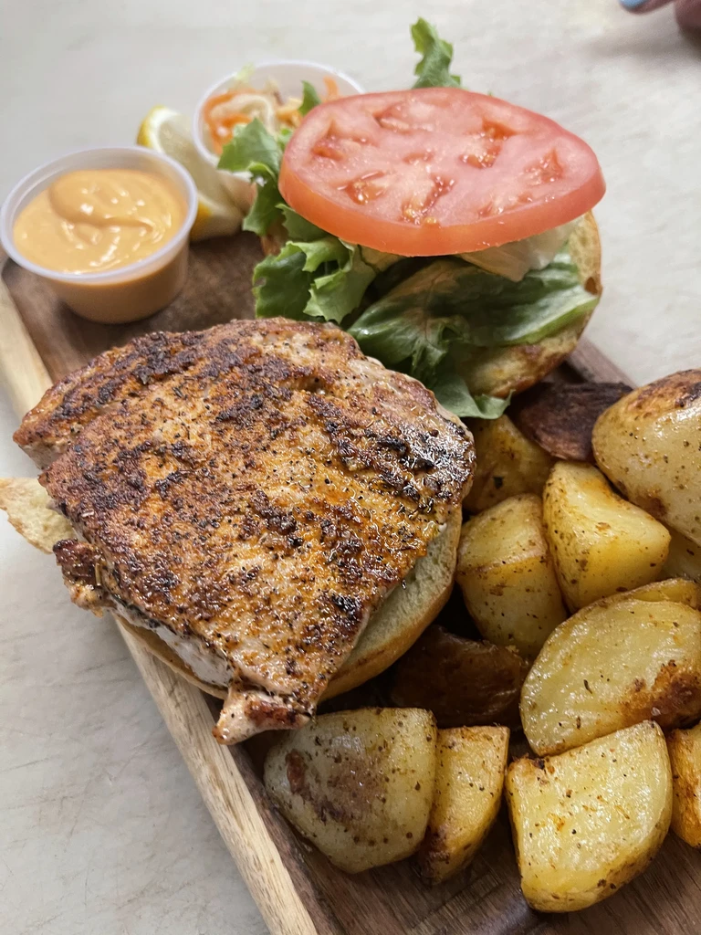 Grilled fish or chicken sandwich, potato wedges, sauce, and coleslaw.