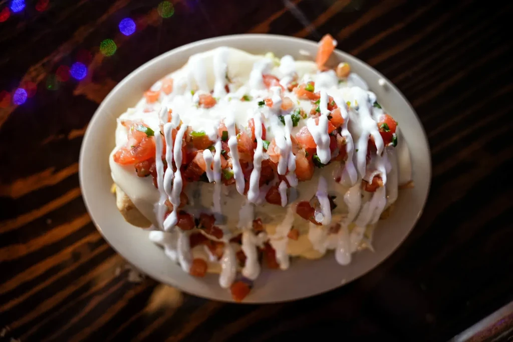 Creamy enchilada-style dish topped with red tomatoes and green herbs.