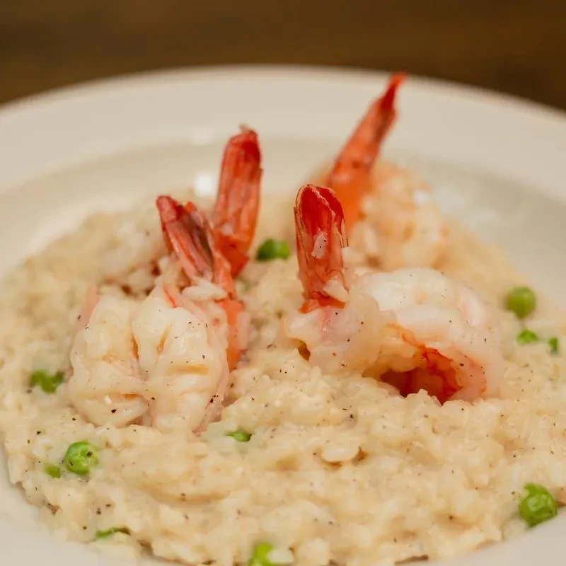 Creamy risotto with green peas topped with three large shrimp.