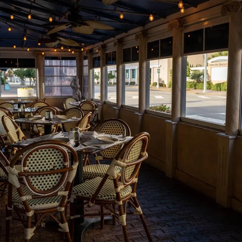 Empty restaurant dining area with woven wicker chairs and warm lighting.
