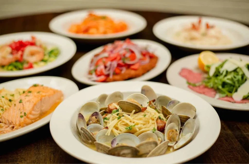 Plated Italian food, spaghetti with clams in focus on a dark table.