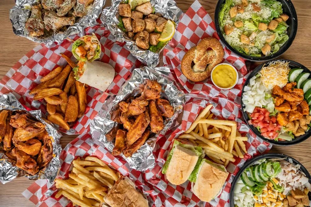 Overhead: Large casual food spread with chicken, fries, salads, and wraps.