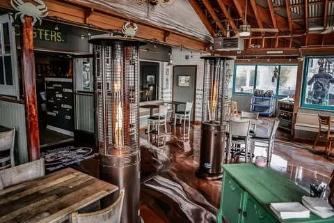 Rustic restaurant with beamed ceiling, marbled floor, gas heaters, and fish menu.