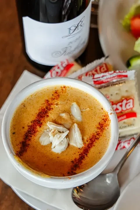Overhead close-up of creamy crab bisque, garnished with crab and seasoning.