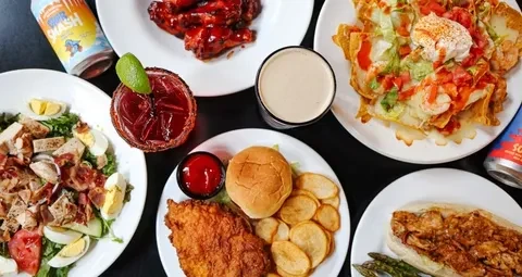 Flat lay of diverse food dishes and beverages on a dark table.