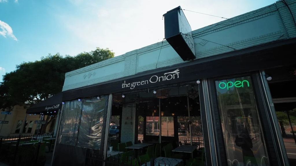 Restaurant 'the green Onion' exterior with patio, awning, and open sign.
