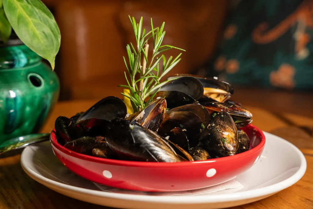 Glistening mussels in a red polka-dot bowl with rosemary and lemon.