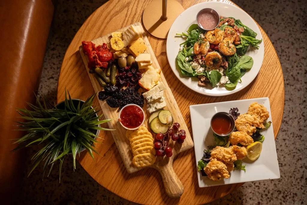 Top-down view of charcuterie board, shrimp salad, and fried seafood.