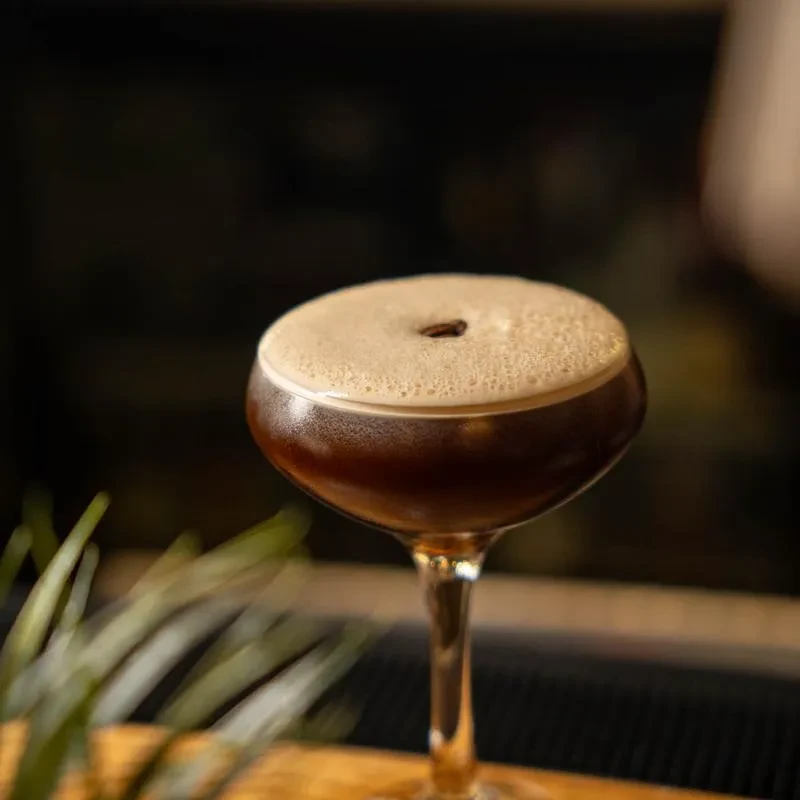 Espresso Martini in coupe glass, frothy head, single coffee bean.
