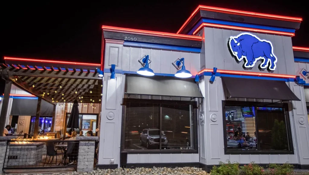Modern restaurant exterior at night with blue buffalo logo and lit patio.