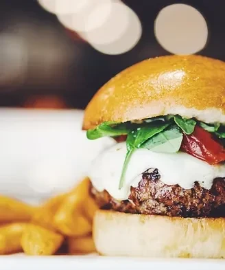 Close-up of a burger with melted cheese and thick-cut fries.