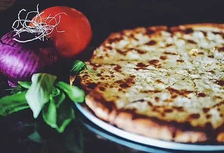 Golden-crust, pre-cut pizza with melted cheese, fresh tomato, onion, and basil.