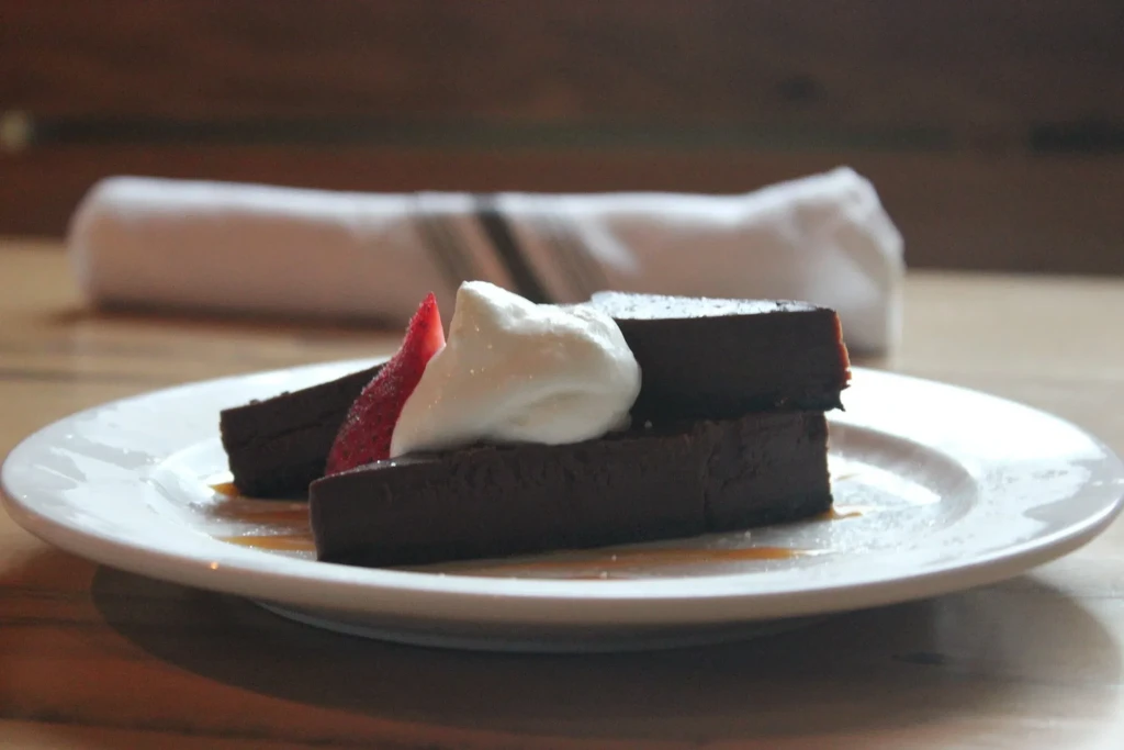 Dark chocolate cake slices with cream, strawberry, and caramel drizzle.