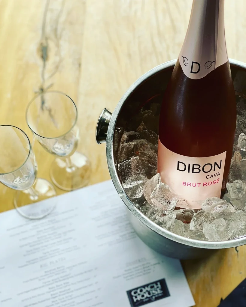 Dibon Cava Brut Rosé bottle in ice bucket, with glasses and menu.
