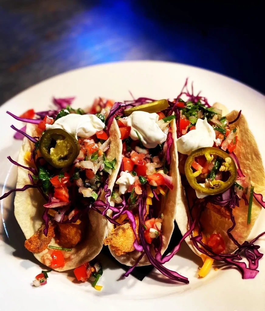 Three loaded soft-shell tacos with fried filling, pico, cabbage, and jalapeño.