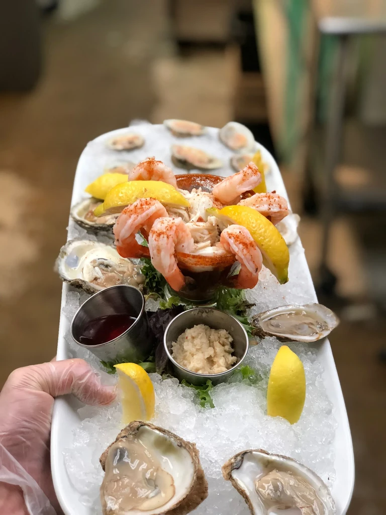 Fresh seafood tower platter with oysters, shrimp, crab, lemons, and sauces.