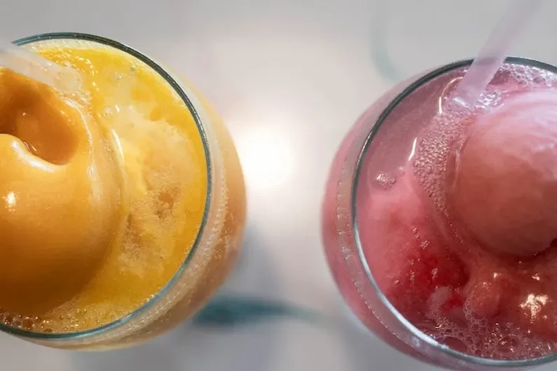 Top-down view of two colorful, icy blended drinks with straws.