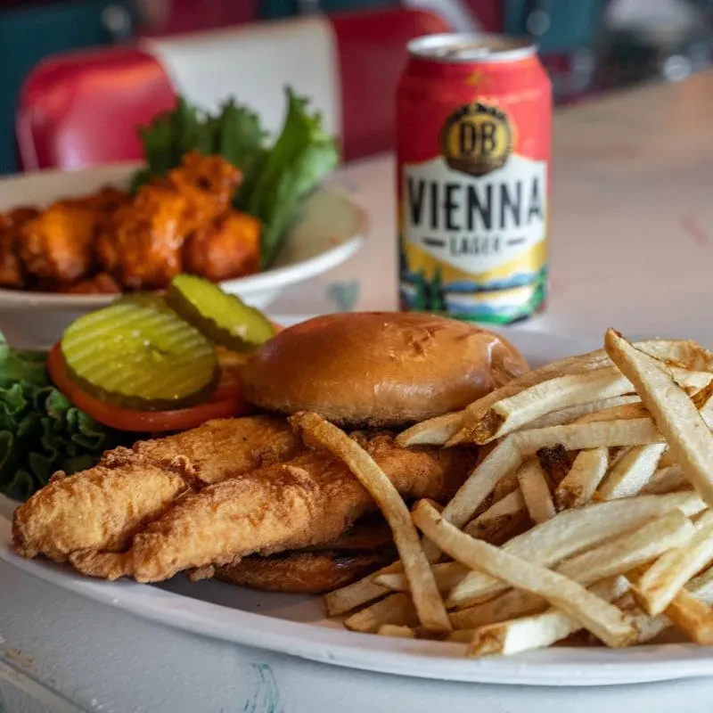 Crispy chicken sandwich with fries, buffalo wings, and a lager beer.