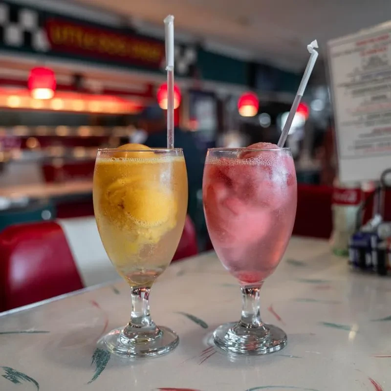 Yellow and pink ice cream drinks with straws in a retro diner.