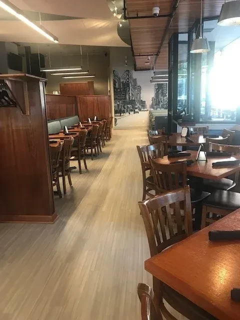 Empty modern restaurant dining area with wooden tables and a city mural.