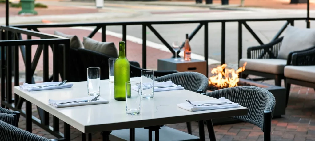 Outdoor restaurant patio with set table, fire pit, and lounge chairs.