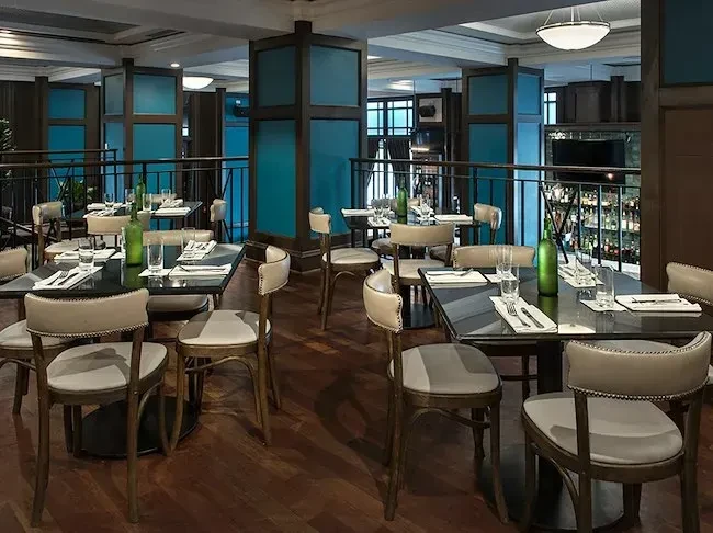 Empty modern restaurant dining area with set tables and a bar.