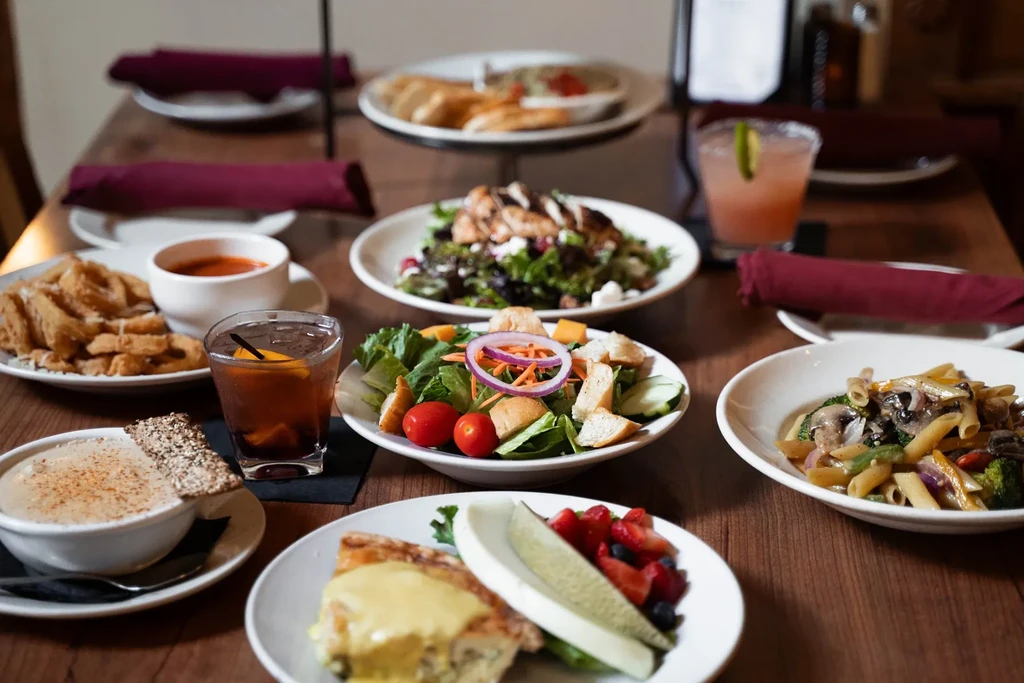 Overhead view of a restaurant table filled with diverse, colorful food and drinks.