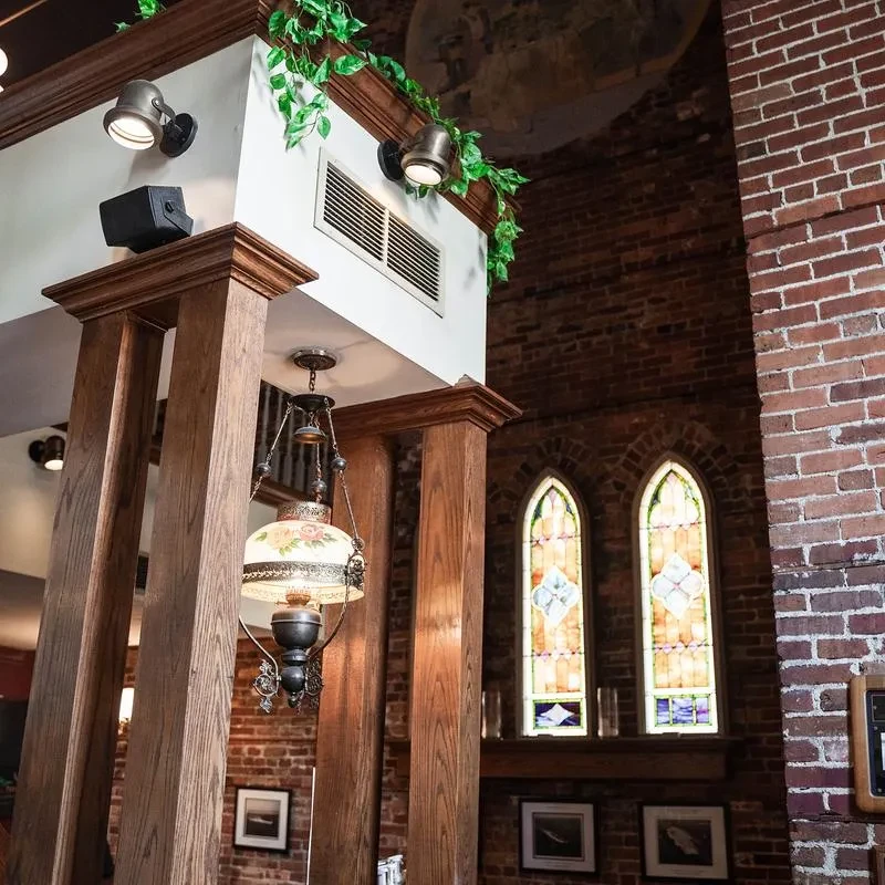 Restaurant interior: wooden pillars, vintage floral lamp, brick, stained glass.
