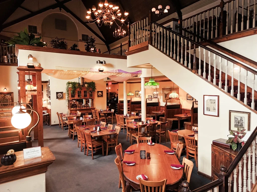 Interior of an empty, warm, multi-level restaurant with wooden tables.