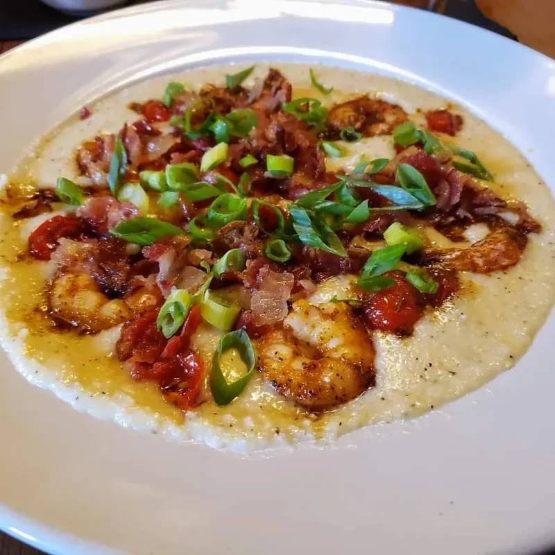 Creamy dish topped with shrimp, bacon, tomatoes, and green onions.