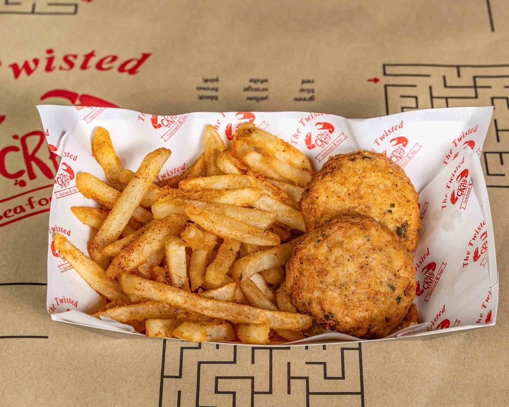 Two golden-brown crab cakes and seasoned fries in a branded paper tray.
