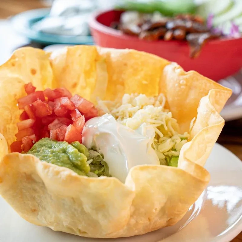Taco salad in a crispy tortilla bowl with tomatoes, guacamole, sour cream.