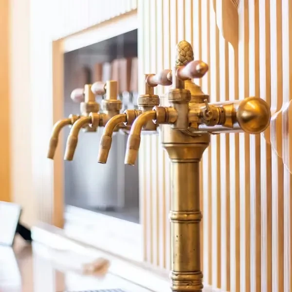 Four ornate brass beer taps against a modern striped wall.