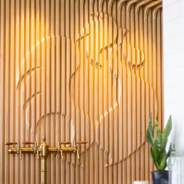 Modern wooden slat wall with backlit abstract pattern and brass beverage dispenser.