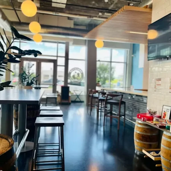Modern industrial bar interior with high-top table and wooden barrels.
