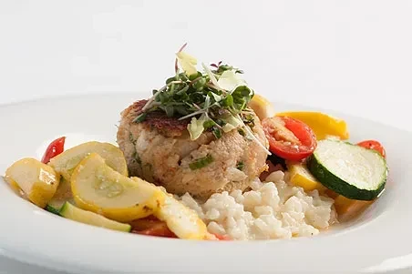 Pan-seared patty with microgreens, rice, sliced squash, and cherry tomatoes.