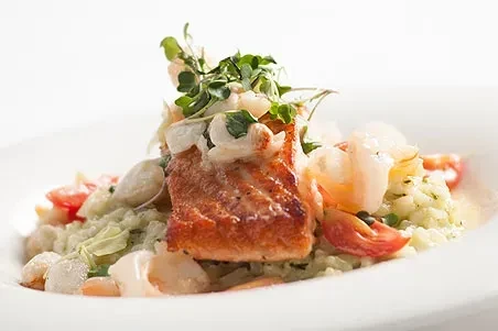 Pan-seared salmon with crispy skin, shrimp, cherry tomatoes, and risotto.