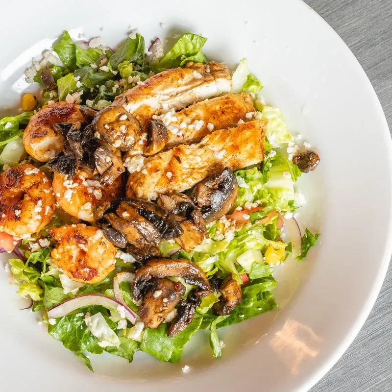 Overhead grilled chicken and shrimp salad with feta and mushrooms.