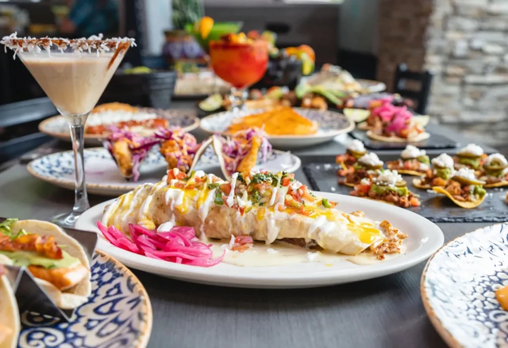 Vibrant Mexican restaurant spread with a burrito, tacos, and colorful cocktails.