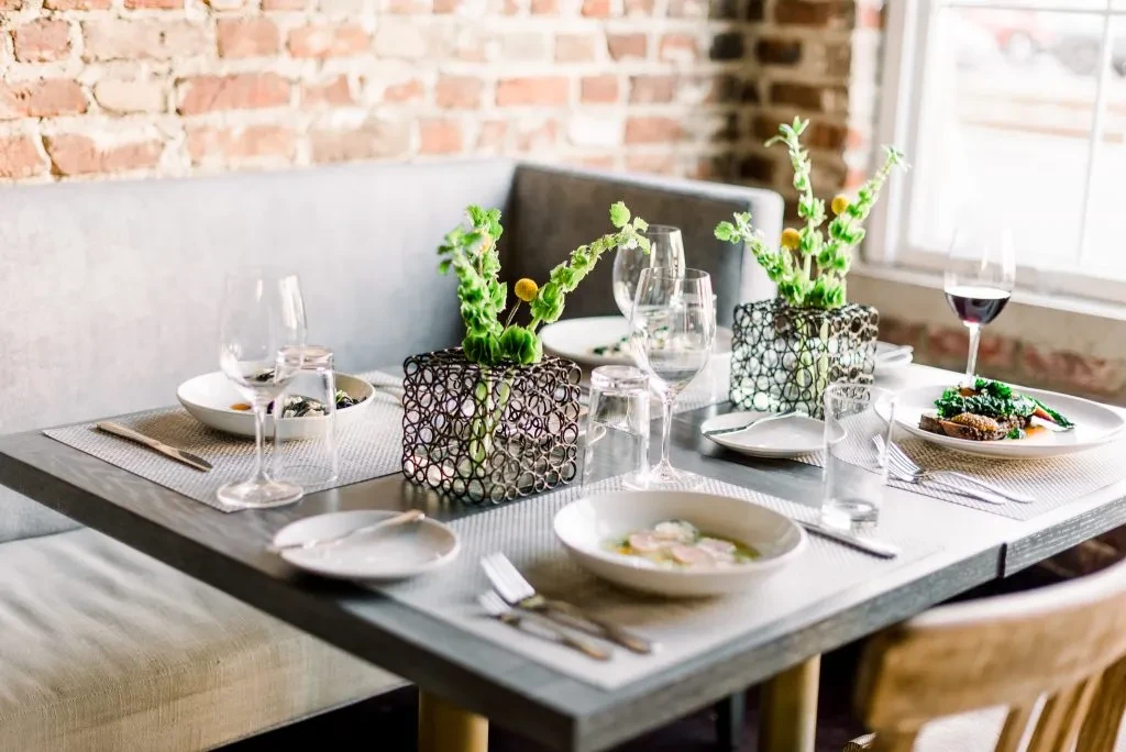Restaurant dining table featuring various dishes, drinks, and decorative centerpieces.