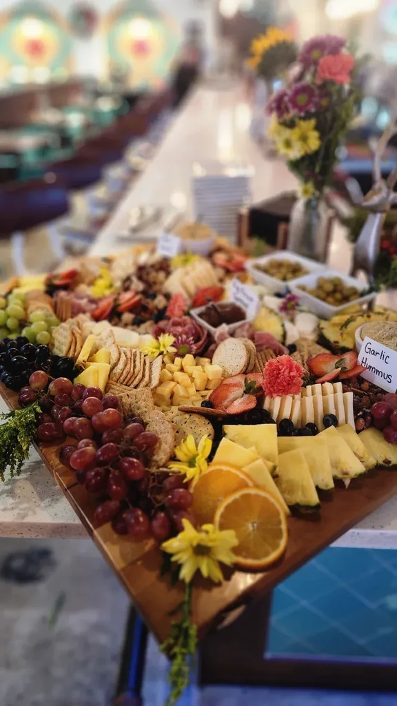An abundant charcuterie board with cheeses, fruits, meats, crackers, nuts, and dips.