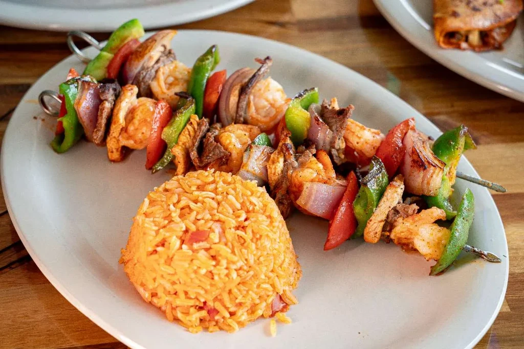Grilled shrimp and meat kabobs with peppers, onions, and Mexican rice.