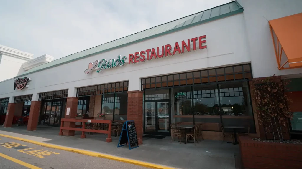 Guads Restaurante exterior in strip mall with outdoor seating and 'OPEN' sign.