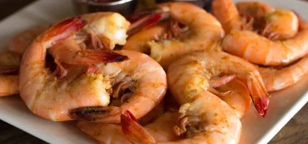 White plate piled high with seasoned, pinkish-orange cooked shrimp.