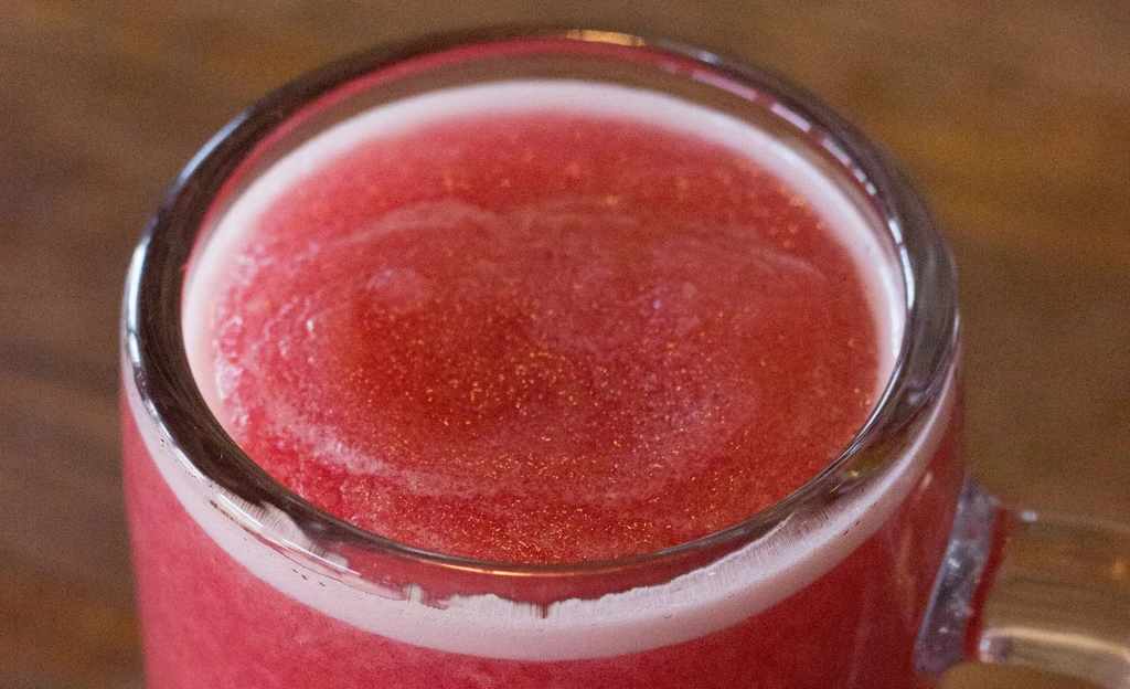 Clear glass mug with a frothy red frozen drink.