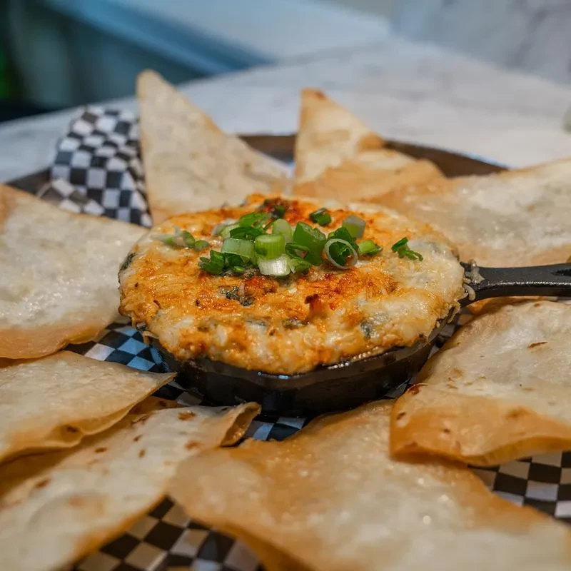 Bubbly baked dip in skillet, garnished with green onions and chips.